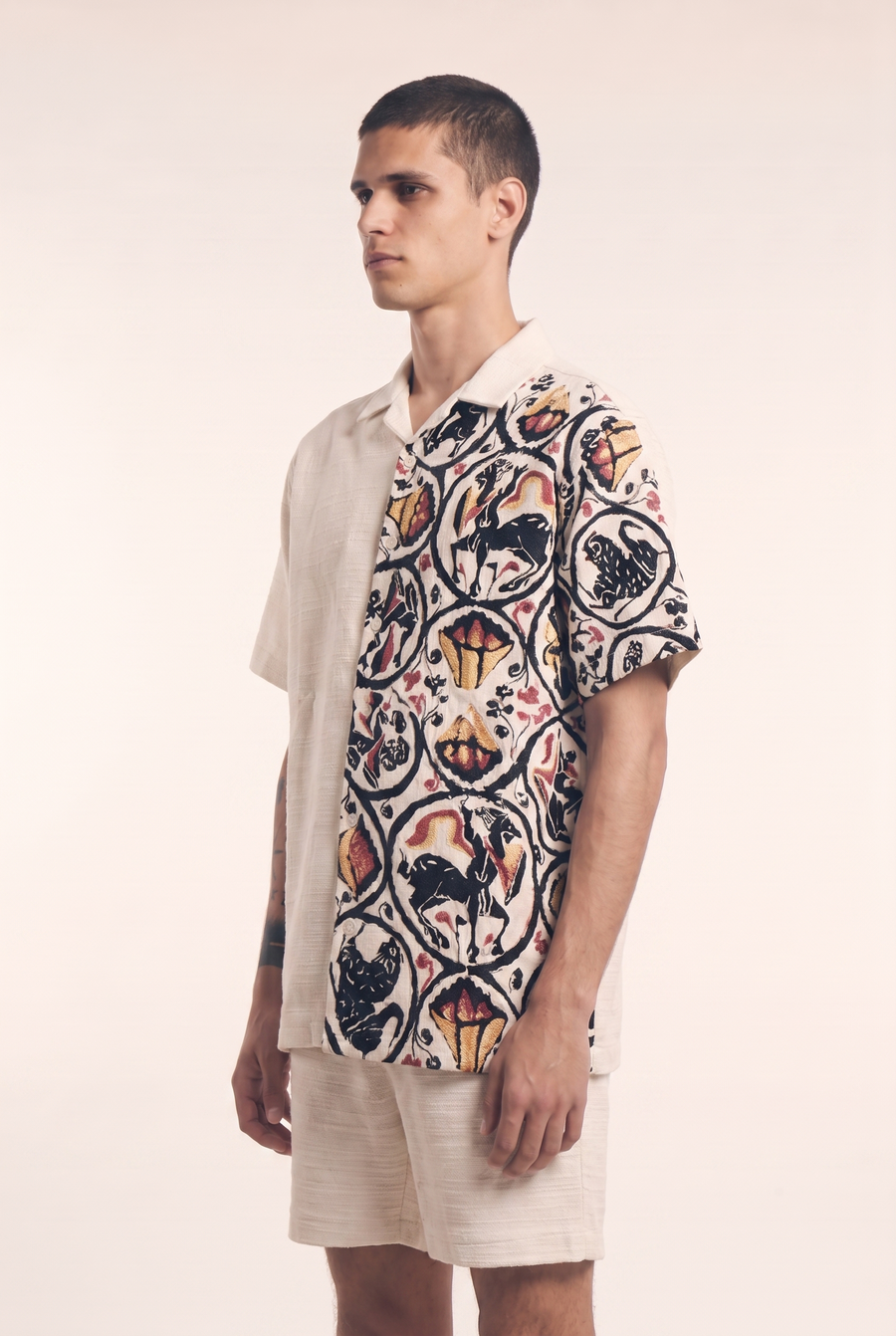 Beige button-up shirt with embroidered Centaur motif, side flat lay