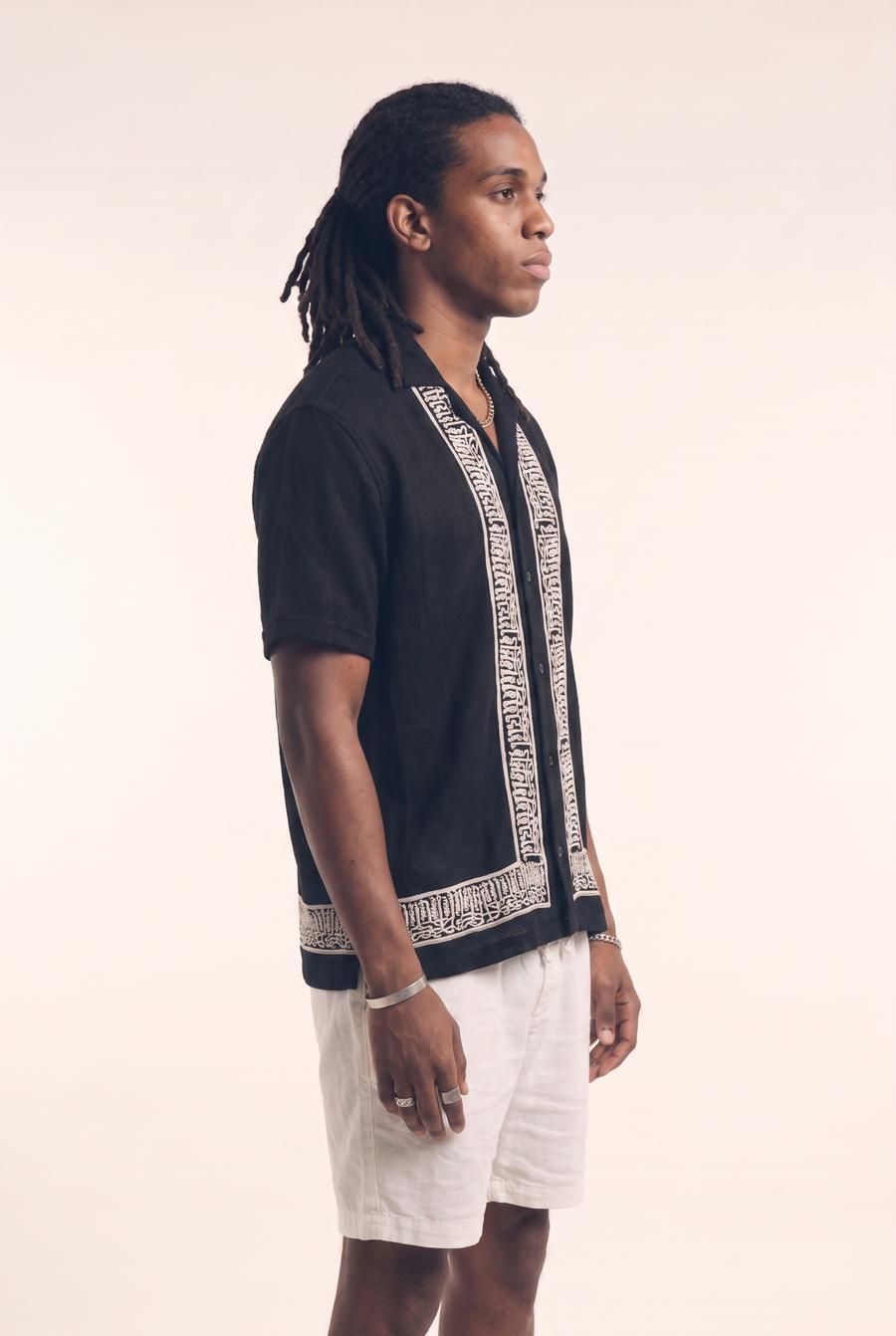 Black button-up shirt with embroidered calligraphy, side flat lay